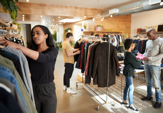 customers browsing clothes on garment rails in a fashion shop